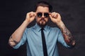 Portrait of a tattooed handsome middle-aged man with beard and hairstyle dressed in a blue shirt and tie, pose with hand Royalty Free Stock Photo