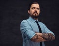 Portrait of a tattooed handsome middle-aged man with beard and hairstyle dressed in a blue shirt and tie, pose in a Royalty Free Stock Photo