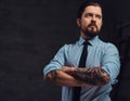 Portrait of a tattooed handsome middle-aged man with beard and hairstyle dressed in a blue shirt and tie, pose in a Royalty Free Stock Photo