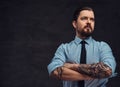 Portrait of a tattooed handsome middle-aged man with beard and hairstyle dressed in a blue shirt and tie, pose in a Royalty Free Stock Photo