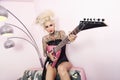 Portrait of a tattooed woman wearing corset while holding guitar against wall