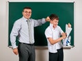 Portrait of a teacher catch the ear funny schoolboy with low discipline. Pupil very emotional, having fun and very happy, posing