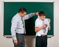 Portrait of a teacher catch the ear funny schoolboy with low discipline. Pupil very emotional, having fun and very happy, posing Royalty Free Stock Photo