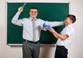 Portrait of a teacher catch the ear funny schoolboy with low discipline. Pupil very emotional, having fun and very happy, posing Royalty Free Stock Photo