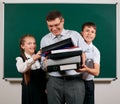 Portrait of a teacher dressed in business suit with folders, documents and briefcase, posing with schoolboy and schoolgirl at