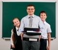 Portrait of a teacher dressed in business suit with folders, documents and briefcase, posing with schoolboy and schoolgirl at