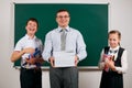 Portrait of a teacher, schoolboy and schoolgirl get a lot of books, posing with notebooks, pens, pencils and other school supplies Royalty Free Stock Photo