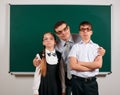 Portrait of a teacher, schoolboy and schoolgirl with old fashioned eyeglasses posing on blackboard background - back to school and Royalty Free Stock Photo