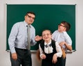 Portrait of a teacher, schoolboy and schoolgirl with old fashioned eyeglasses posing on blackboard background - back to school and Royalty Free Stock Photo