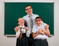 Portrait of a teacher, schoolboy and schoolgirl with old fashioned eyeglasses posing on blackboard background - back to school and