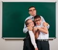 Portrait of a teacher, schoolboy and schoolgirl with old fashioned eyeglasses posing on blackboard background - back to school and Royalty Free Stock Photo