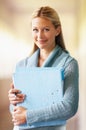 Portrait, teacher and woman with folder in hallway of school with pride for career or job. Education, binder and serious