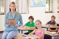 Portrait, teacher and woman with children in classroom, smile and holding folder. Happiness, female educator and