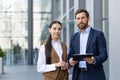 Portrait of a team and partners of a young business man and woman standing outside the office center with documents in Royalty Free Stock Photo