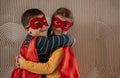 Portrait of a team of two young superheroes, brother and sister, over beige background