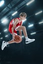 Portrait of teen boy, professional basketball player scoring goal in a jump  over sport stadium background Royalty Free Stock Photo