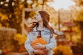 Portrait of teen girl with long hair posing with pumpkin at the open farm market place. Autumn background
