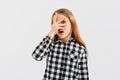 Portrait of teen girl looking shocked and concerned, hiding face behind hands, peeking through fingers frightened, watching horror Royalty Free Stock Photo