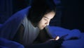 Portrait of teenage girl lying in bed at night and using smart phone Royalty Free Stock Photo