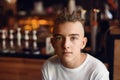 Portrait of a teen guy with short dreadlocks and a white t-shirt in a cafe Royalty Free Stock Photo