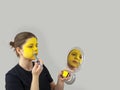 Portrait teenage actress girl painting face with yellow brush and paint,looking in mirror.Playing in theater.Copy space Royalty Free Stock Photo