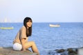 Portrait of teenage asian girl sitting on the stone near the sea Royalty Free Stock Photo