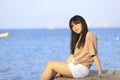 Portrait of teenage asian girl sitting on the stone near the sea Royalty Free Stock Photo