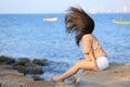 Portrait of teenage asian girl sitting on the stone near the sea Royalty Free Stock Photo