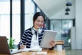 Portrait of a teenage Asian woman using a tablet, wearing headphones and using a notebook to study online via video Royalty Free Stock Photo