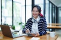 Portrait of a teenage Asian woman using a tablet, wearing headphones and using a notebook to study online via video Royalty Free Stock Photo