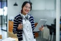 Portrait of a teenage Asian woman using a tablet, wearing headphones and using a notebook to study online via video Royalty Free Stock Photo
