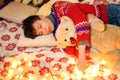 Portrait of teenage boy sleeping in new year or christmas decoration. Holiday lights, gifts and christmas tree decorated with toys Royalty Free Stock Photo