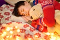 Portrait of teenage boy sleeping in new year or christmas decoration. Holiday lights, gifts and christmas tree decorated with toys Royalty Free Stock Photo