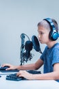 Portrait of teenage boy wearing headphones using computer keyboard and microphone Royalty Free Stock Photo