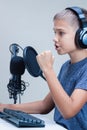 Portrait of teenage boy wearing headphones using computer keyboard and microphone. Royalty Free Stock Photo