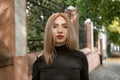 Portrait of teenage girl with blonde hair in black turtleneck outside. Young fair-haired woman looks into the camera Royalty Free Stock Photo