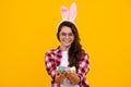 Portrait of teenage girl child wearing bunny ears holding easter eggs isolated at yellow background. Happy teenager Royalty Free Stock Photo