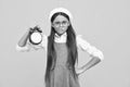 Portrait of teenage girl with clock alrm, time and deadline. Studio shot isolated on yellow background. Angry teenager Royalty Free Stock Photo