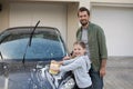 Teenage girl and father washing a car on a sunny day Royalty Free Stock Photo