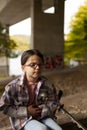 Portrait of a girl with glasses and a plaid shirt sitting on the steps of a bridge Royalty Free Stock Photo