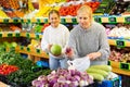 Portrait of teenage girl and her mother who buying fresh vegetables and fruits at shop Royalty Free Stock Photo