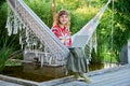 Portrait of teenage girl with laptop sitting in hammock in backyard
