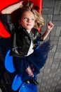 Portrait of the teenage girl lies on the stadium plastic seats. Fashion Kid model.