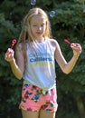 Portrait of a teenage girl long blond hair, with a bubble blower in her hand, who looks surprised at the bubble blowing. The backg Royalty Free Stock Photo