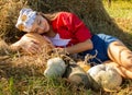 Teenage girl on a pile of hay with pumpkins in a red shirt and bandana