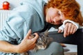 Portrait teenage girl with red hair, cast on arm and domestic cat at home Royalty Free Stock Photo