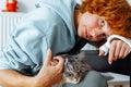 Portrait teenage girl with red hair, cast on arm and domestic cat at home Royalty Free Stock Photo