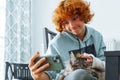 Portrait teenage girl with red hair, cast on arm and domestic cat at home Royalty Free Stock Photo