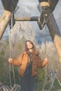 Portrait of a teenage girl standing on a swing and listening to music on a mountain background.