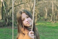 Portrait of a teenage girl standing on a swing and listening to music on a mountain background.